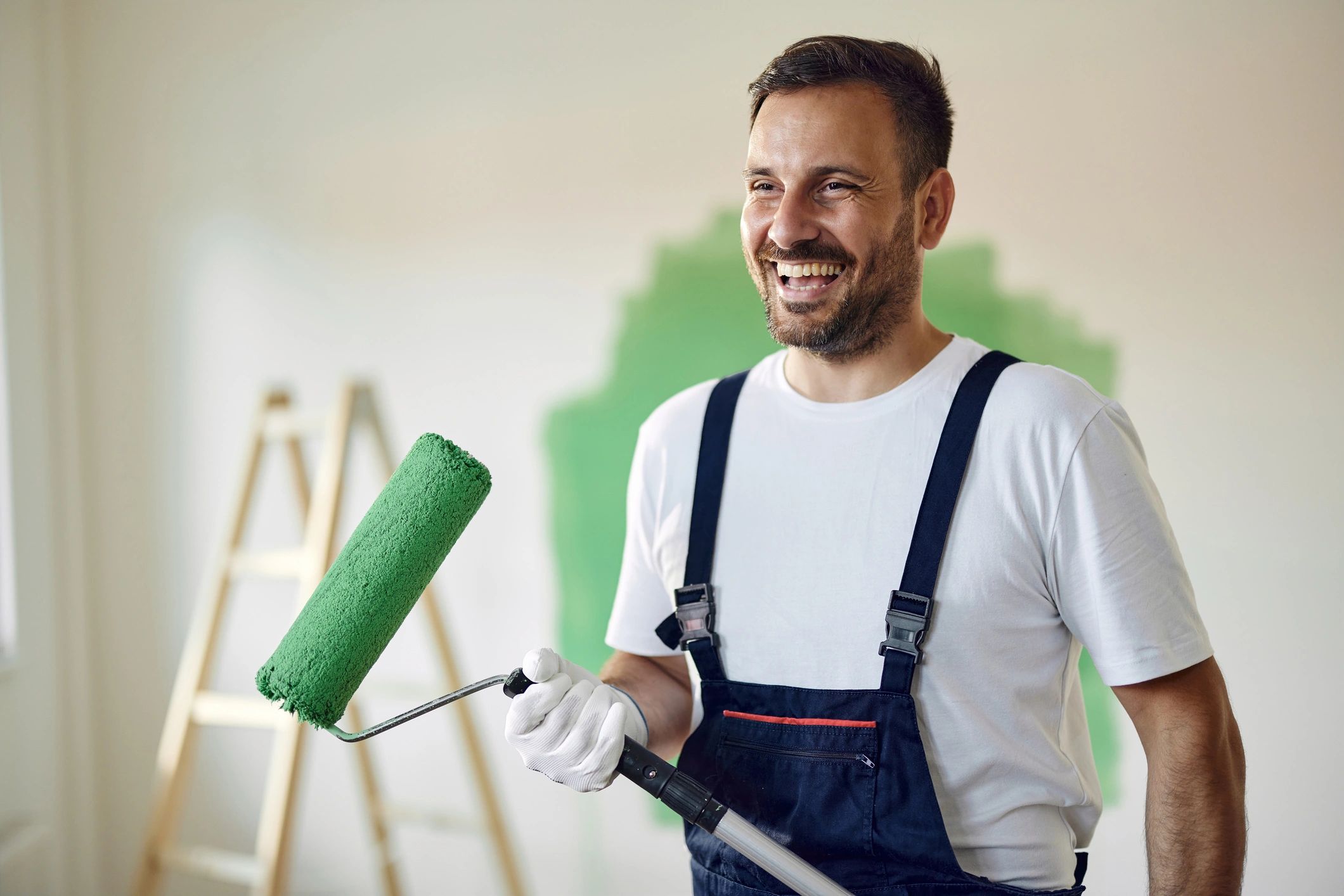 Painter rolling green paint for a smooth, even finish